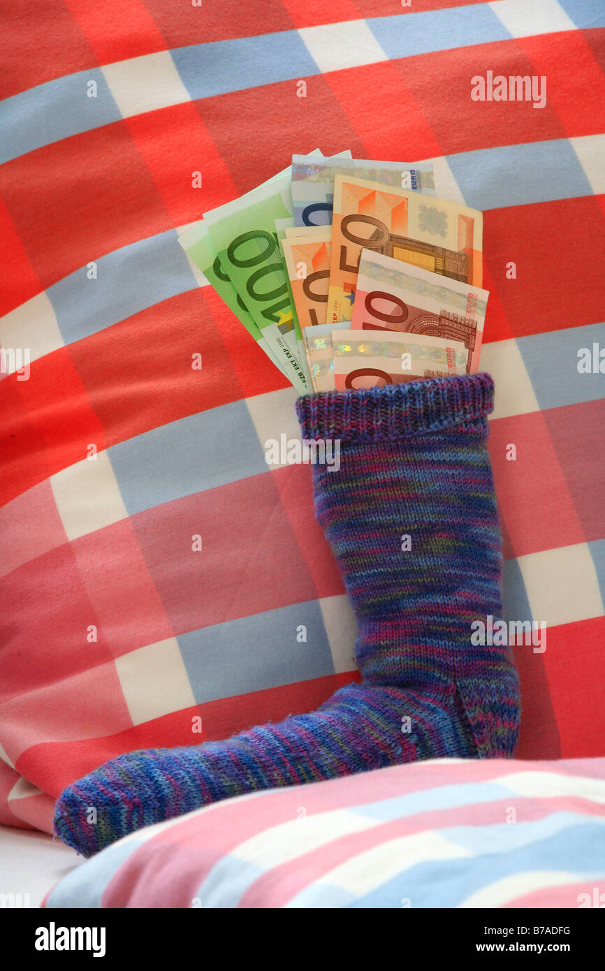 Calza di risparmio su un letto riempito con le banconote in euro, crisi finanziaria ansia Foto Stock