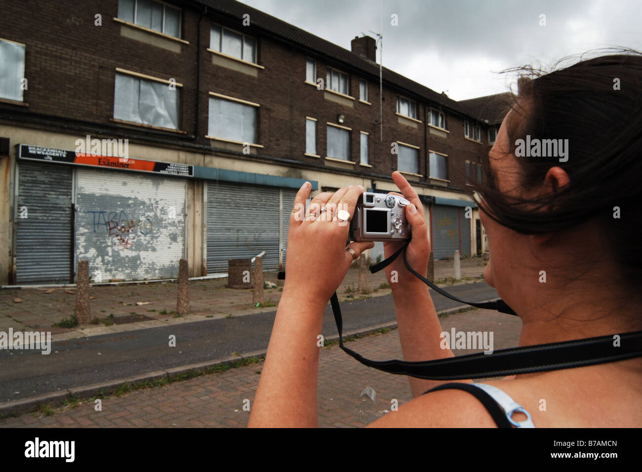 Una donna fotografie malandato negozi al Consiglio estate vive su cui viene migliorata Foto Stock