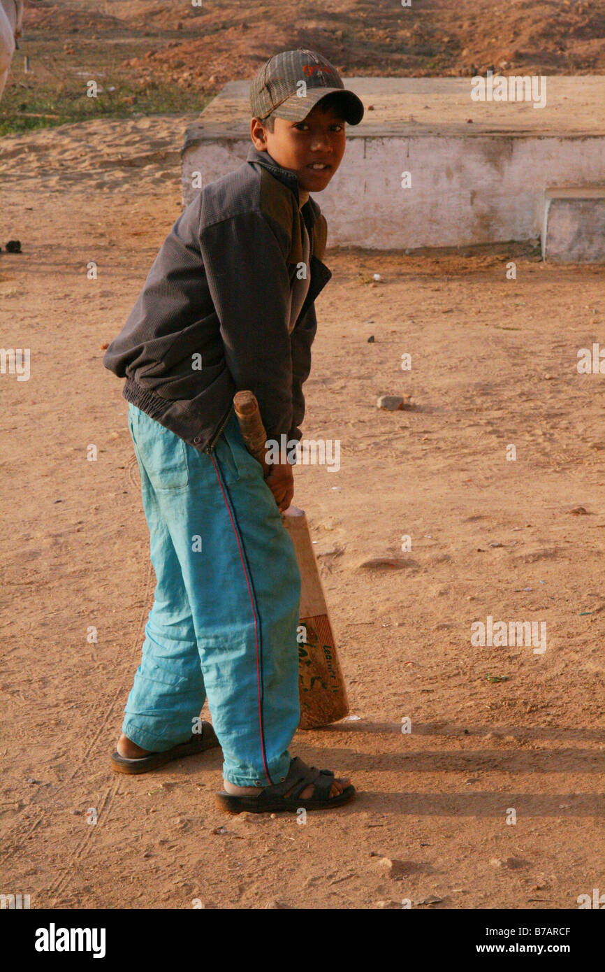 Un giovane ragazzo gioca il cricket al di fuori di casa sua nel villaggio di Mocha, Madhya Pradesh, India Foto Stock