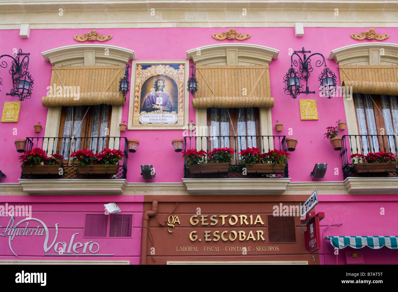 Vivacemente colorato facciata di un edificio con balconi cesti di fiori e i ciechi della finestra Almeria Spagna Foto Stock