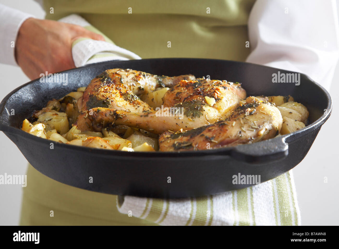 Close-up di arrosto di cosce di pollo arrosto le cipolle e le patate in una padella in ghisa Foto Stock