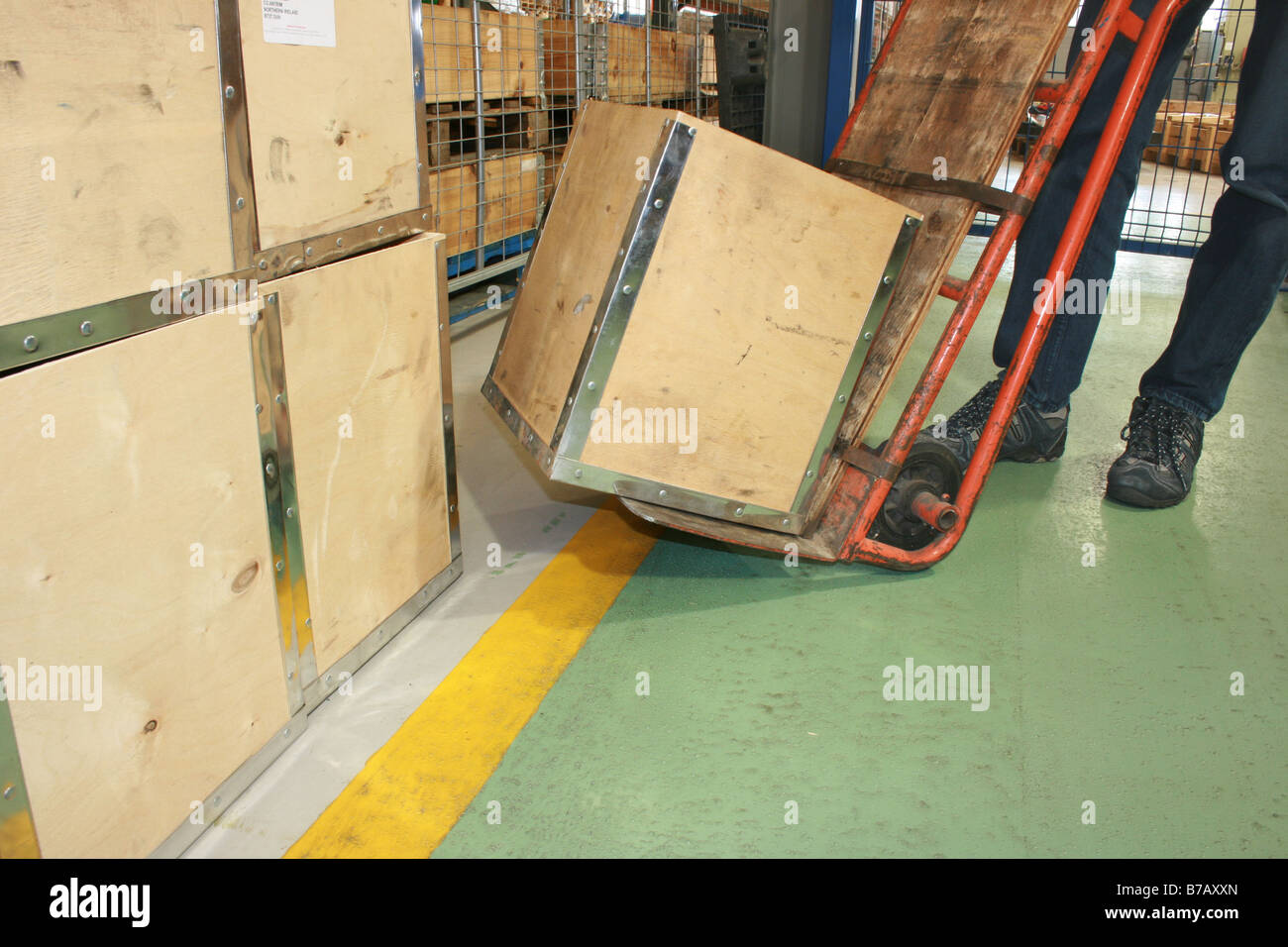 L uomo lo spostamento di una gabbia in legno con una mano il carrello in un magazzino del Regno Unito Foto Stock