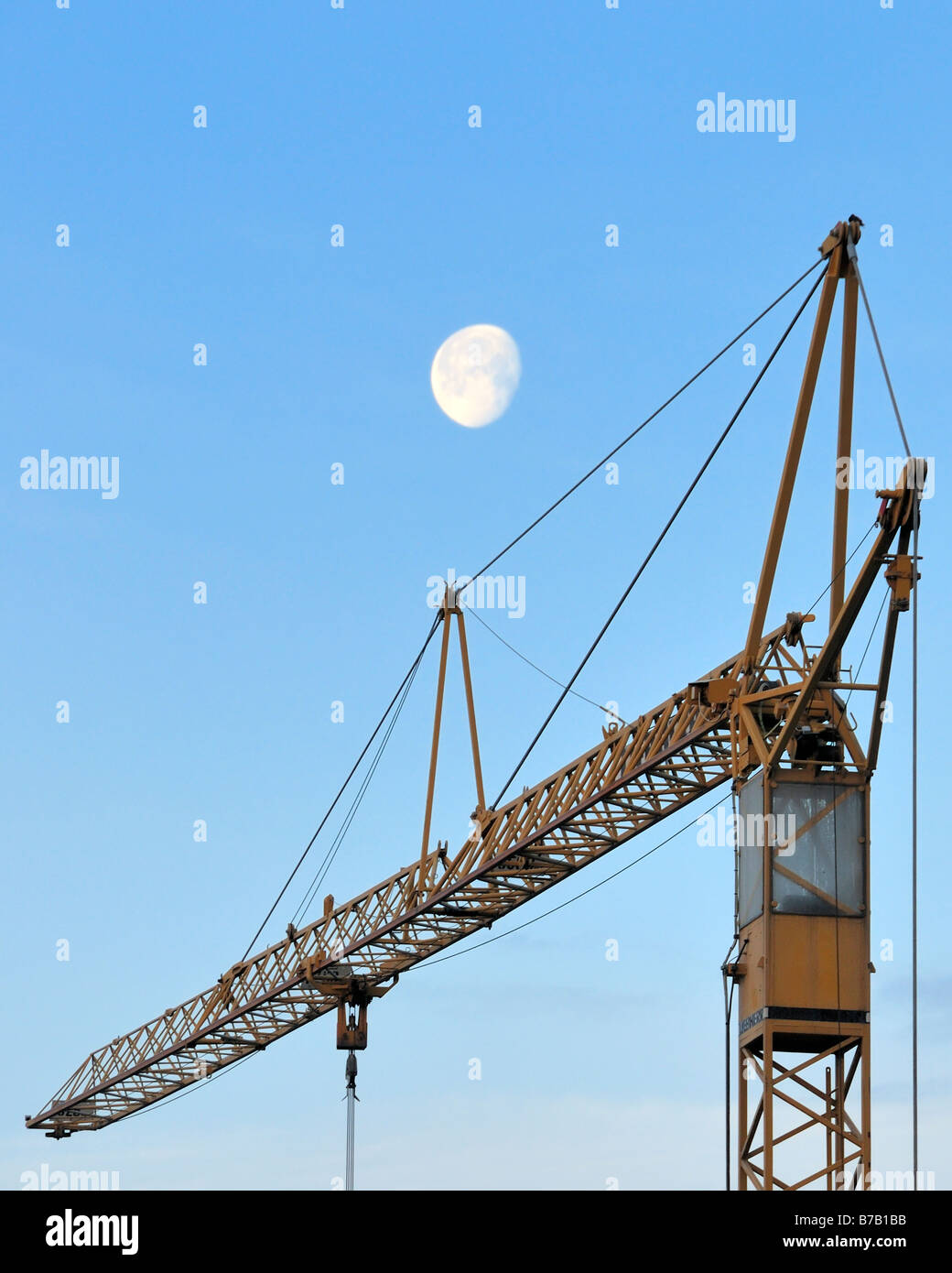 Luna di mattina su una gru da cantiere che simboleggiano il costante cambiamento intorno a noi Foto Stock