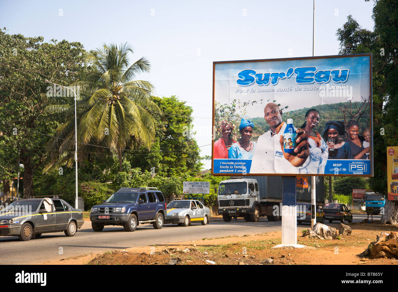 Una pubblicità tramite Affissioni Sur Eau sorge accanto ad una strada trafficata attraverso la Guinea la capitale Conakry. Foto Stock