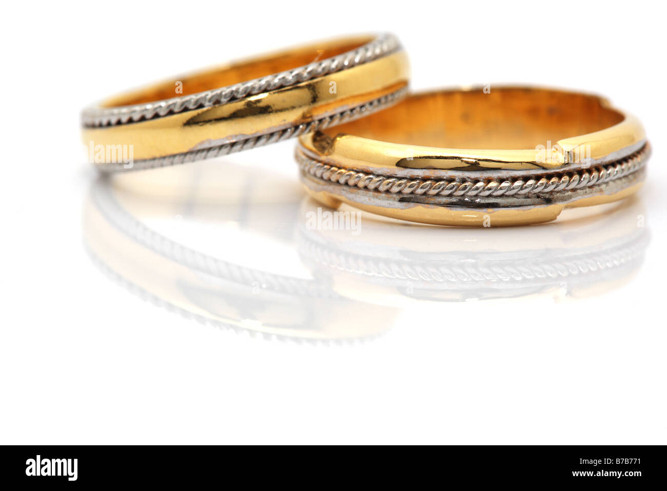 Oro due anelli di nozze closeup riflesso con copyspace su bianco Foto Stock