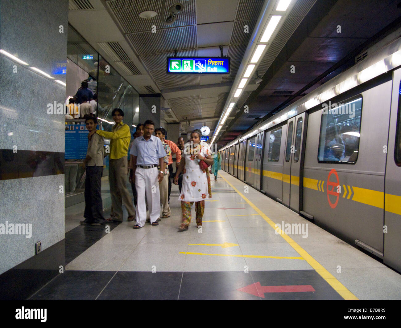 Una linea gialla in treno, e alcuni in partenza passeggeri indiani, in corrispondenza di una piattaforma sulla metropolitana di Delhi del sistema ferroviario. Delhi. India. Foto Stock
