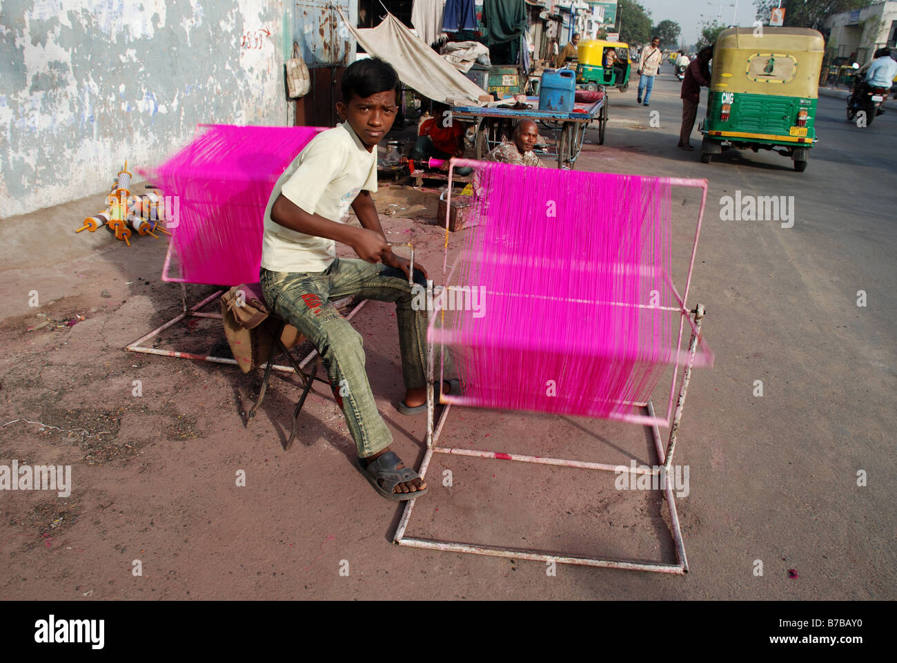Ragazzo di filettatura di tintura in strada in preparazione per il Kite Festival, Ahmedabad, India. Foto Stock