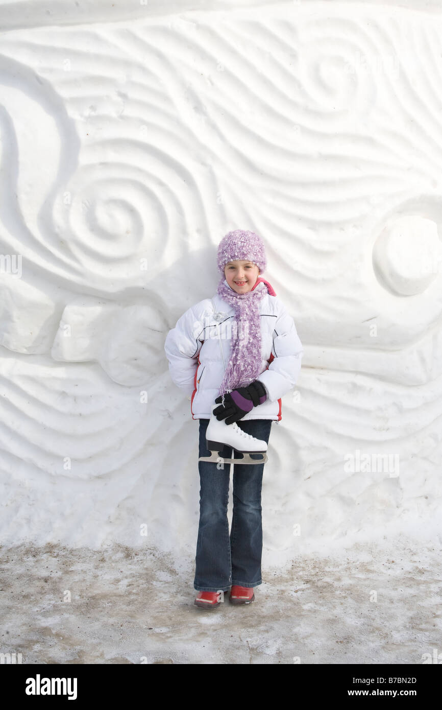 9 anno vecchia ragazza con pattini a fianco di scultura di neve, le forche, Winnipeg, Canada Foto Stock