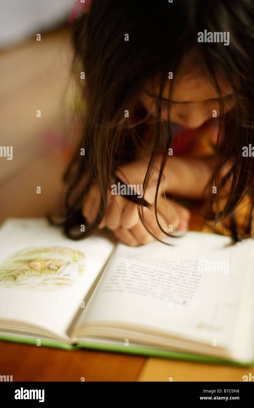 Bambina di cinque anni giace sul piano la lettura di Beatrix Potter prenota Foto Stock