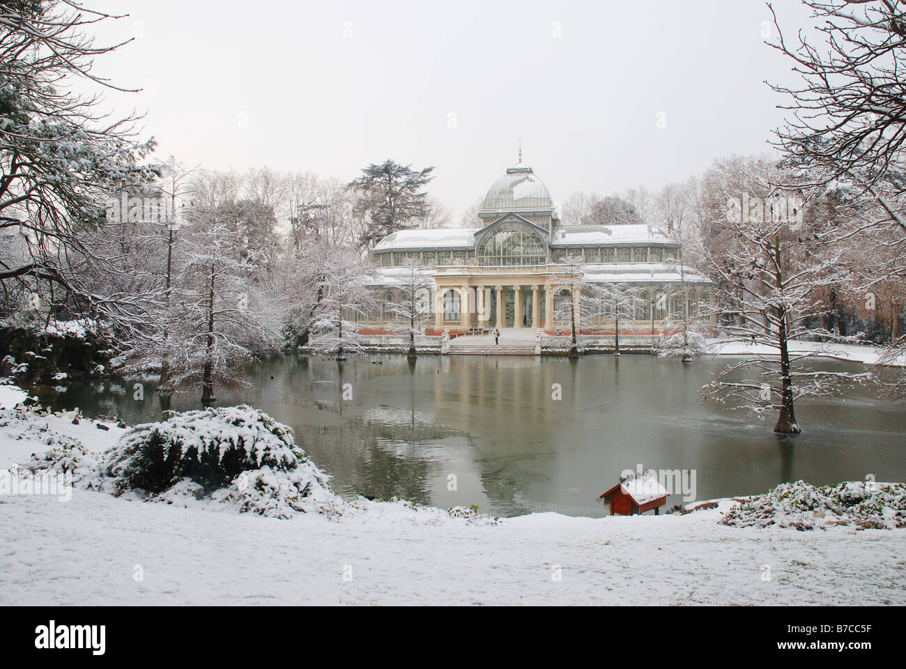 Coperta di neve Palacio de Cristal e stagno. Il Parco del Retiro. Madrid. Spagna. Foto Stock