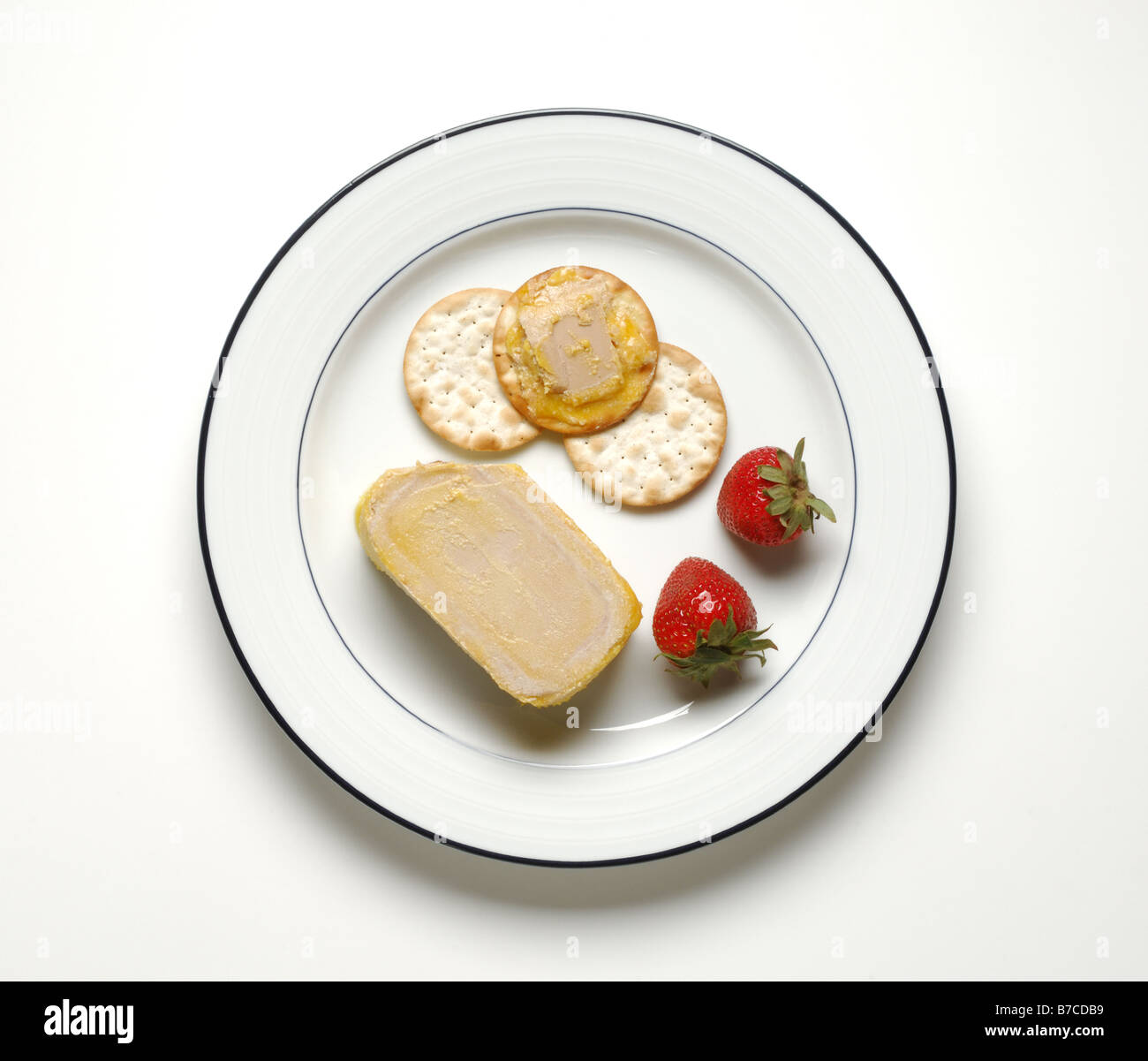 Il foie gras, cracker e fragole su una rotonda bianca piastra cena Foto Stock