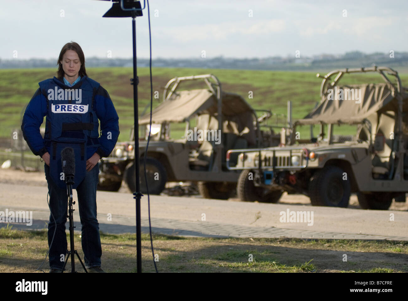Una giornalista televisiva indossa una giacca protettiva contrassegnata con "TV" mentre si prepara per alzarsi in piedi in un complesso dell'esercito israeliano vicino al confine con Gaza, Israele Foto Stock
