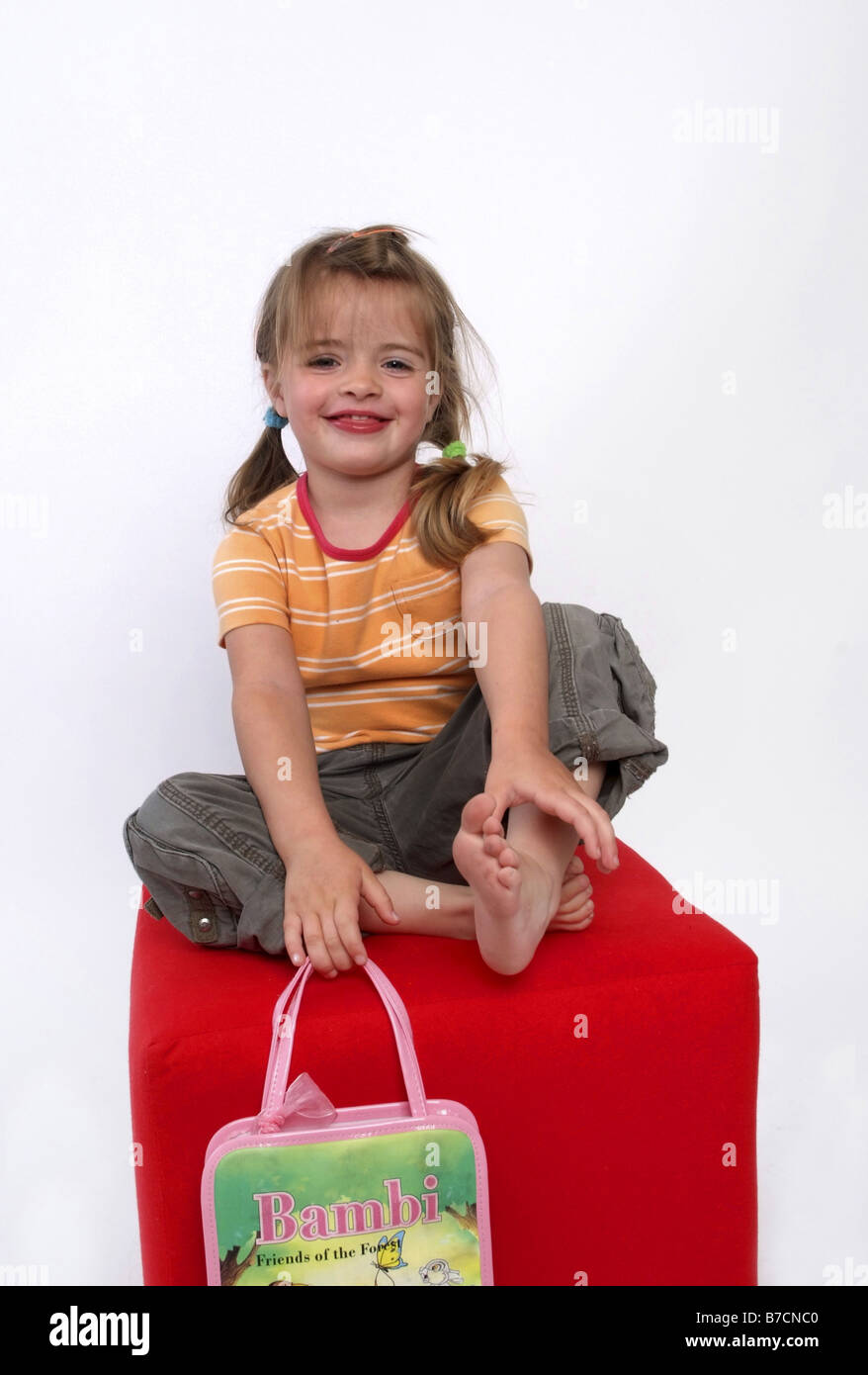 Felice ragazza bionda seduta su un cubo rosso Foto Stock