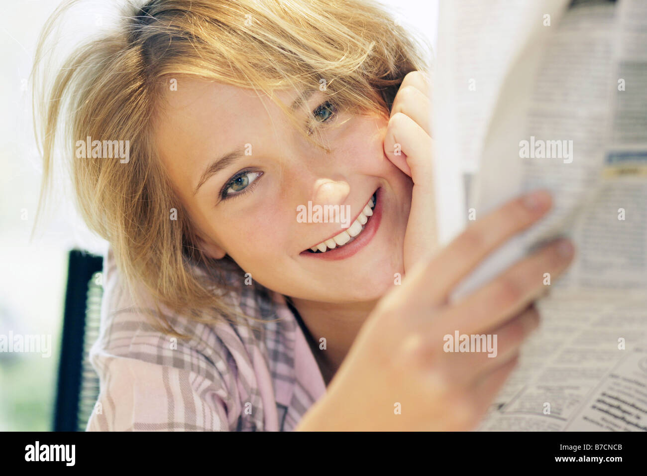 Giovane donna bionda che la lettura di un quotidiano al mattino, Germania Foto Stock