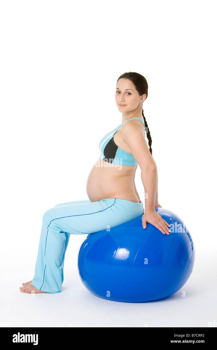 Incinta giovane donna seduta su una sfera di fitness Foto Stock