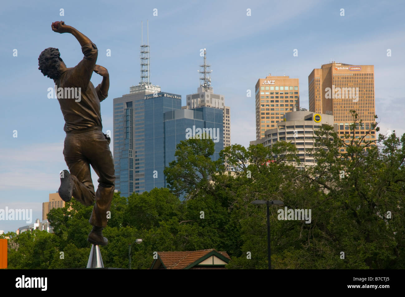Una statua di bronzo di cricketing grande Dennis Lillee al di fuori del MCG bowling in direzione della skyline di Melbourne Foto Stock