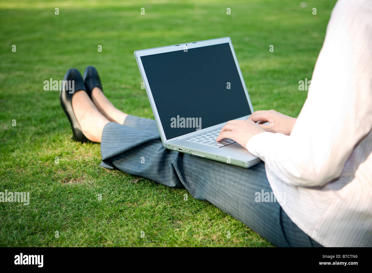 Un business donna siiting sul prato e utilizzando il computer portatile Foto Stock