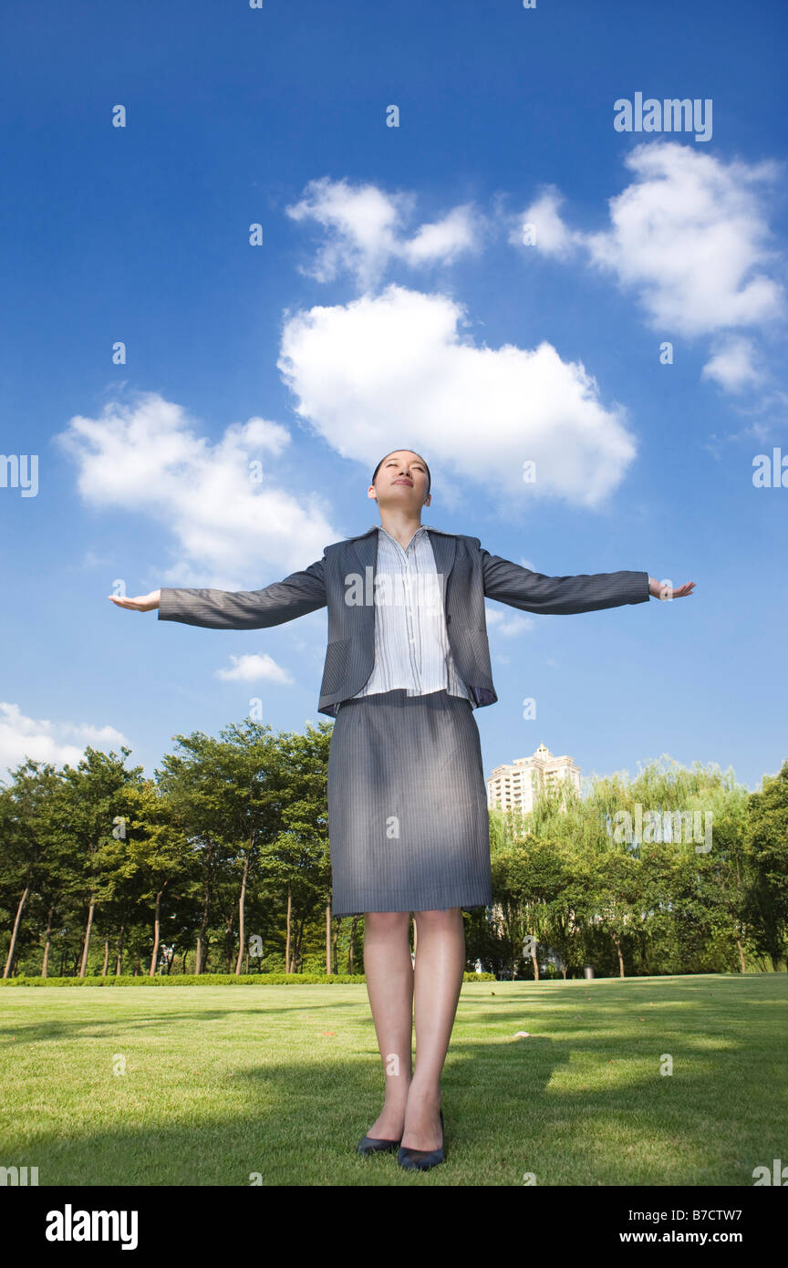 Un business donna in piedi sul prato con le braccia aperte Foto Stock