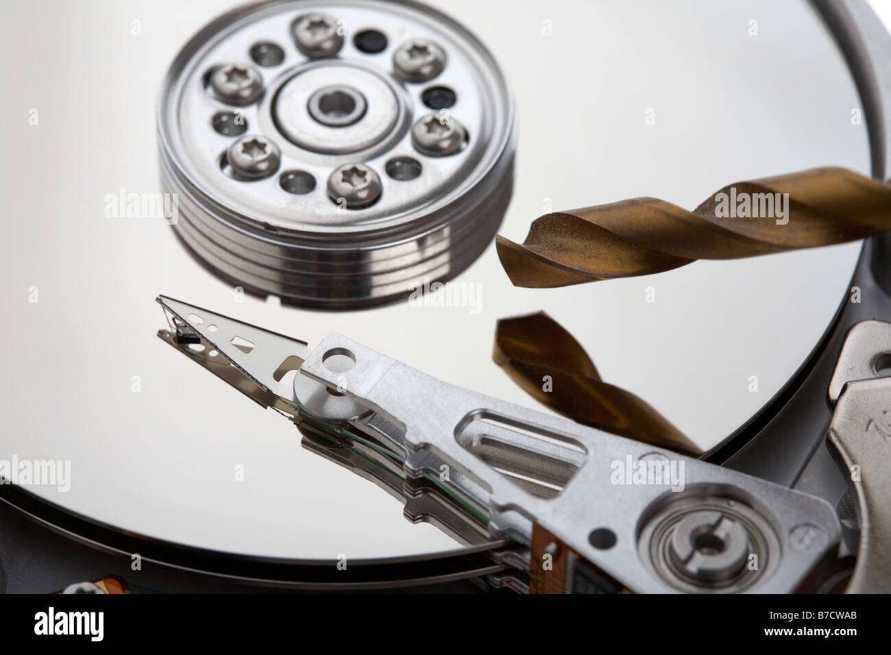 Punta da trapano la perforazione in un aperto unità disco rigido del computer su sfondo bianco Foto Stock