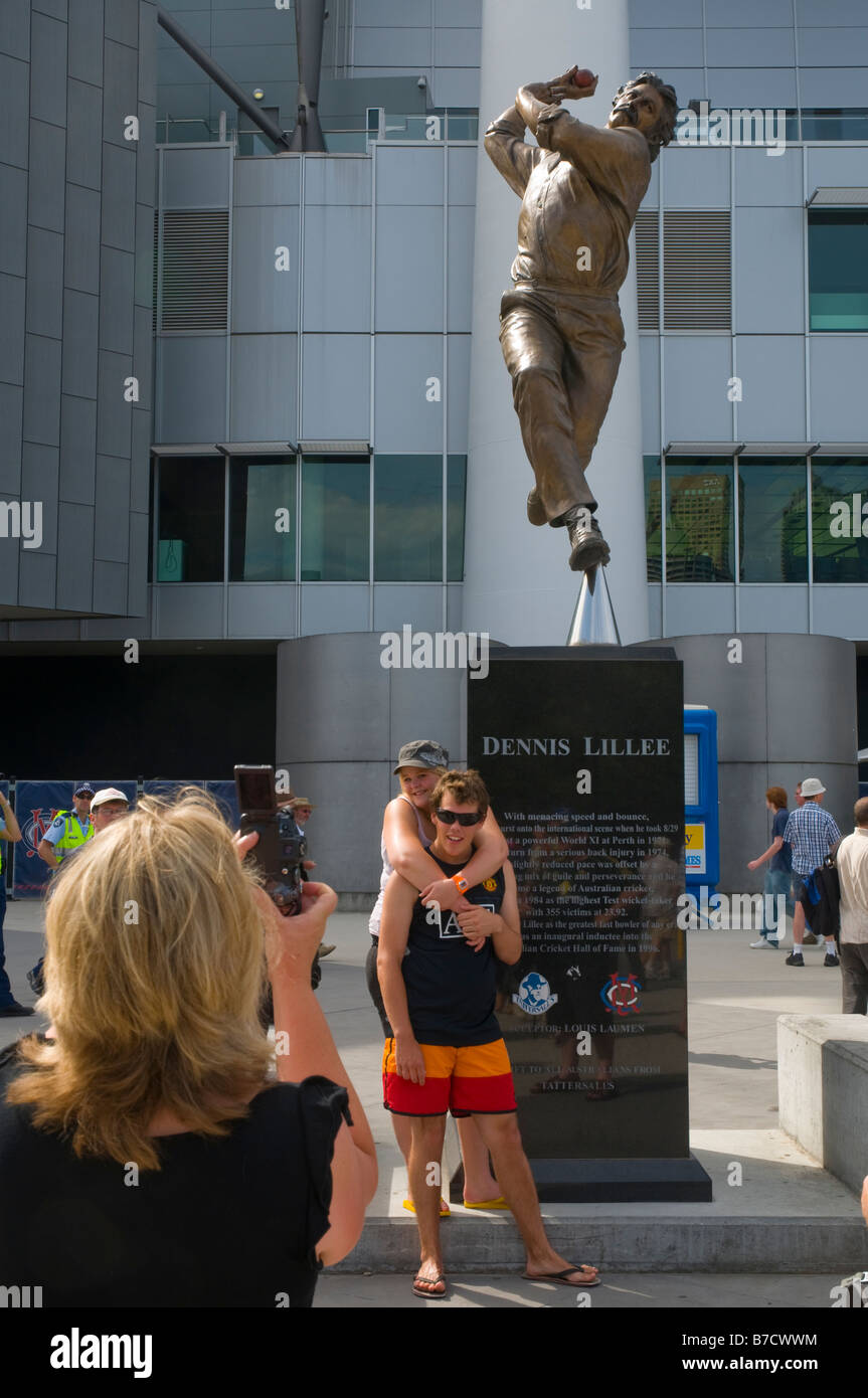 Australian tifosi di cricket che è fotografata sotto una statua del grande cricketing Dennis Lillee presso il MCG Foto Stock