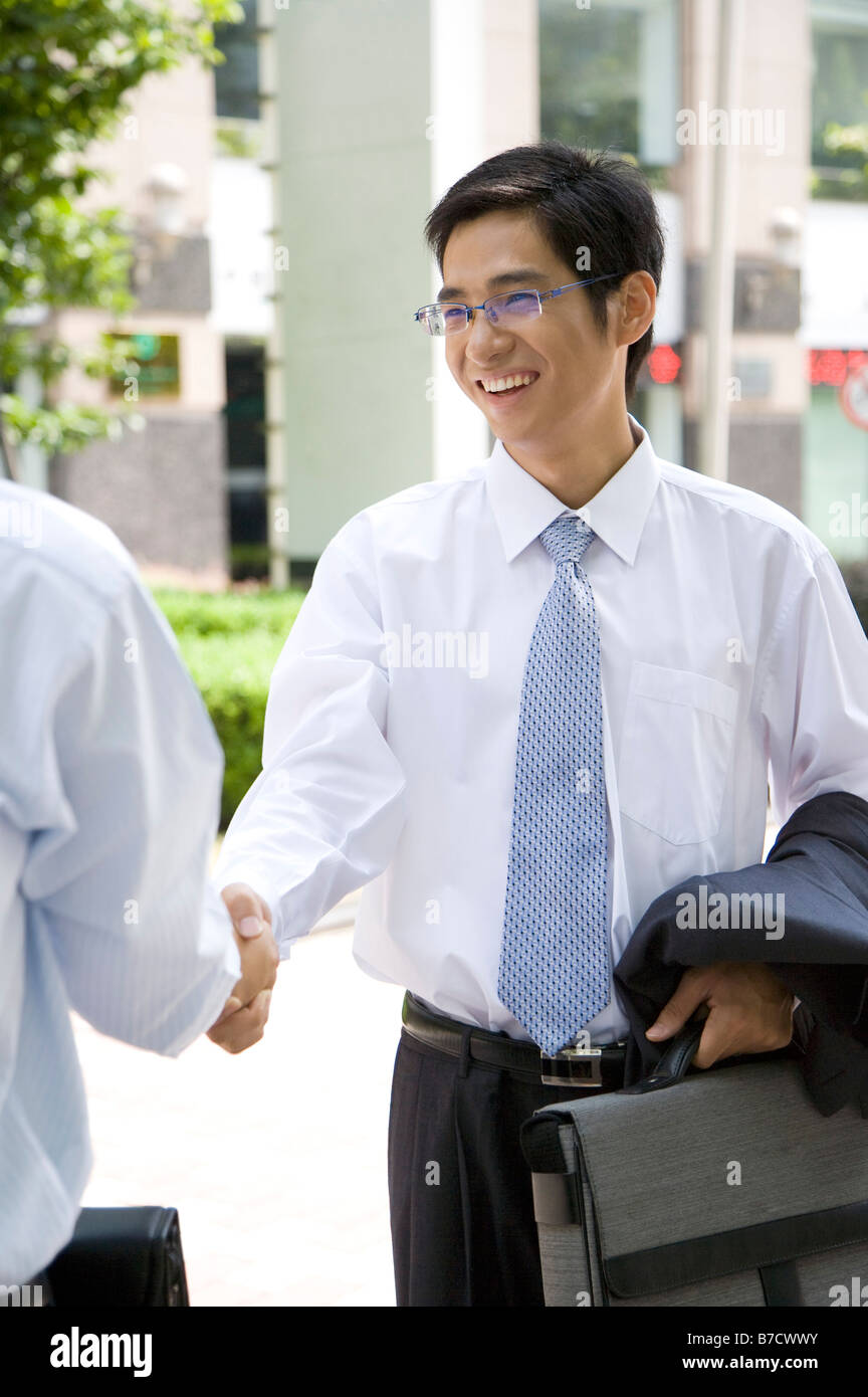 Due uomini di affari si stringono la mano e sorridente felicemente Foto Stock
