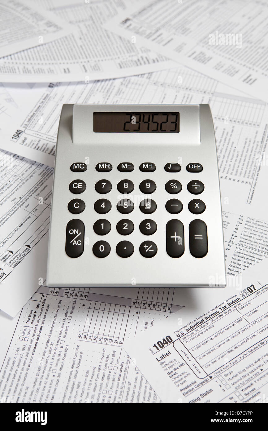 Una calcolatrice sulla parte superiore dei formulari per la dichiarazione delle imposte Foto Stock