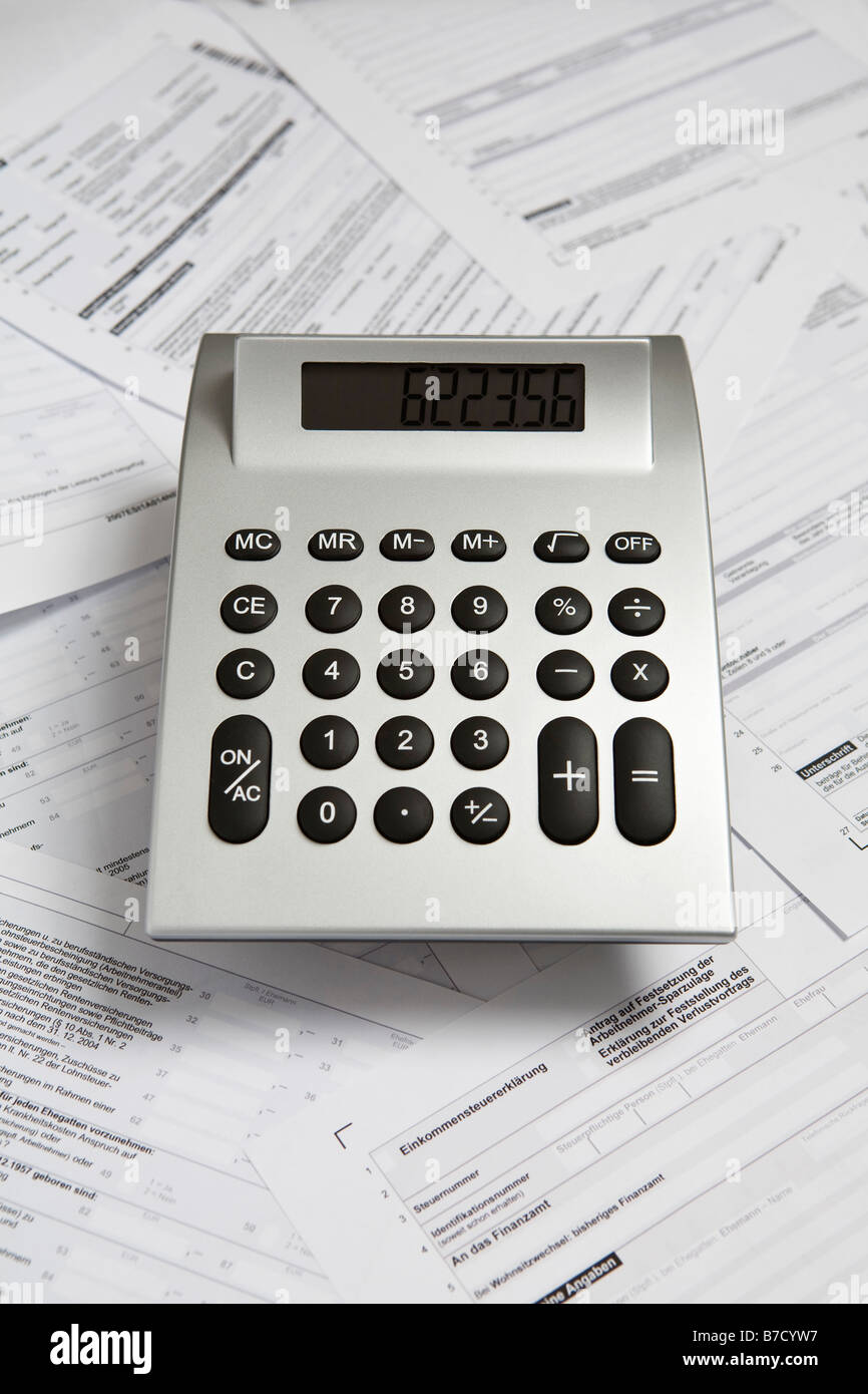 Una calcolatrice sulla parte superiore dei formulari per la dichiarazione delle imposte Foto Stock