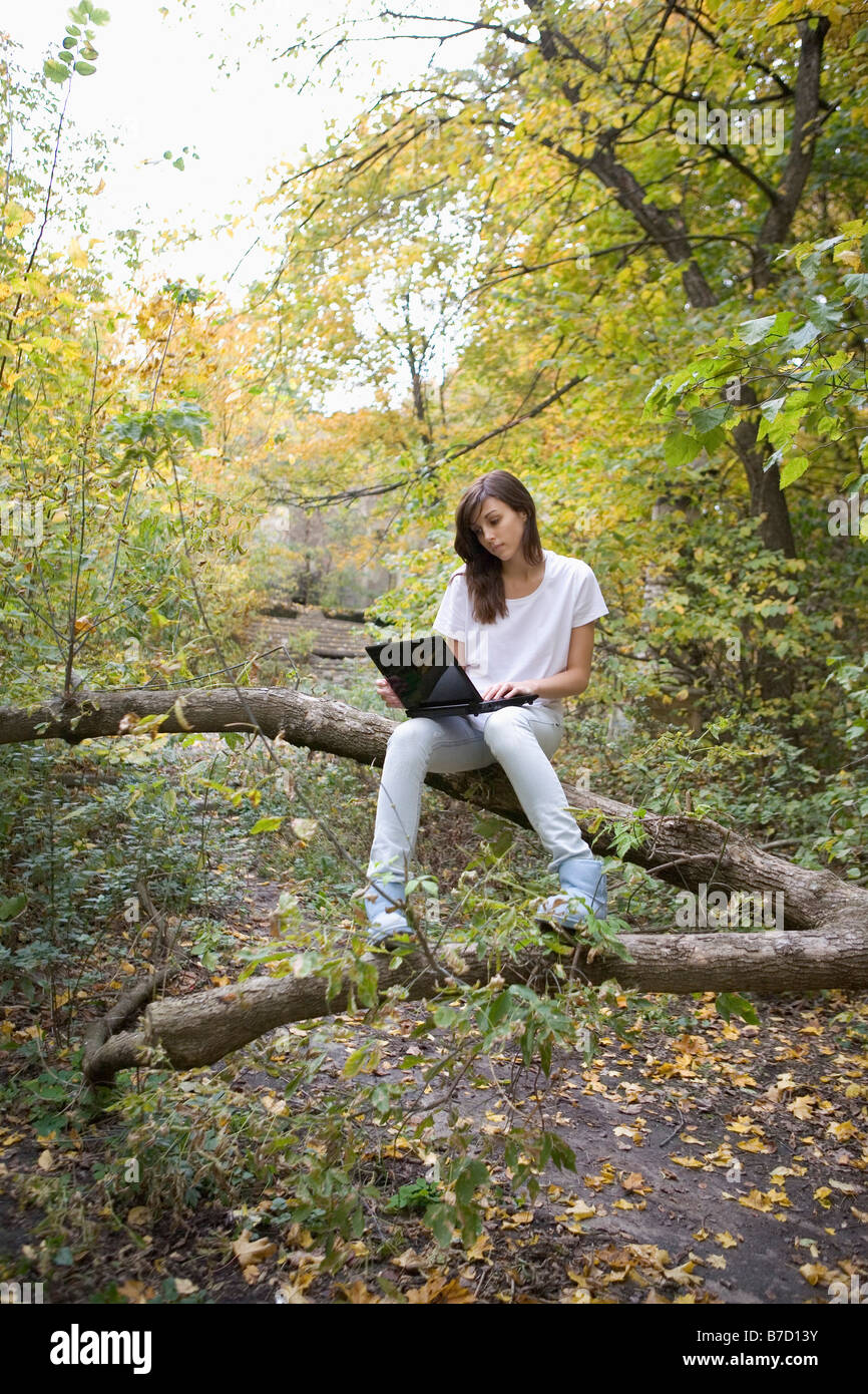 Una ragazza adolescente utilizzando un laptop seduto nella natura Foto Stock