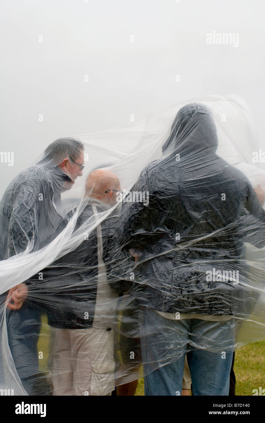 I frequentatori del festival si ripara dalla pioggia sotto teloni di plastica a Hop Farm festival Foto Stock