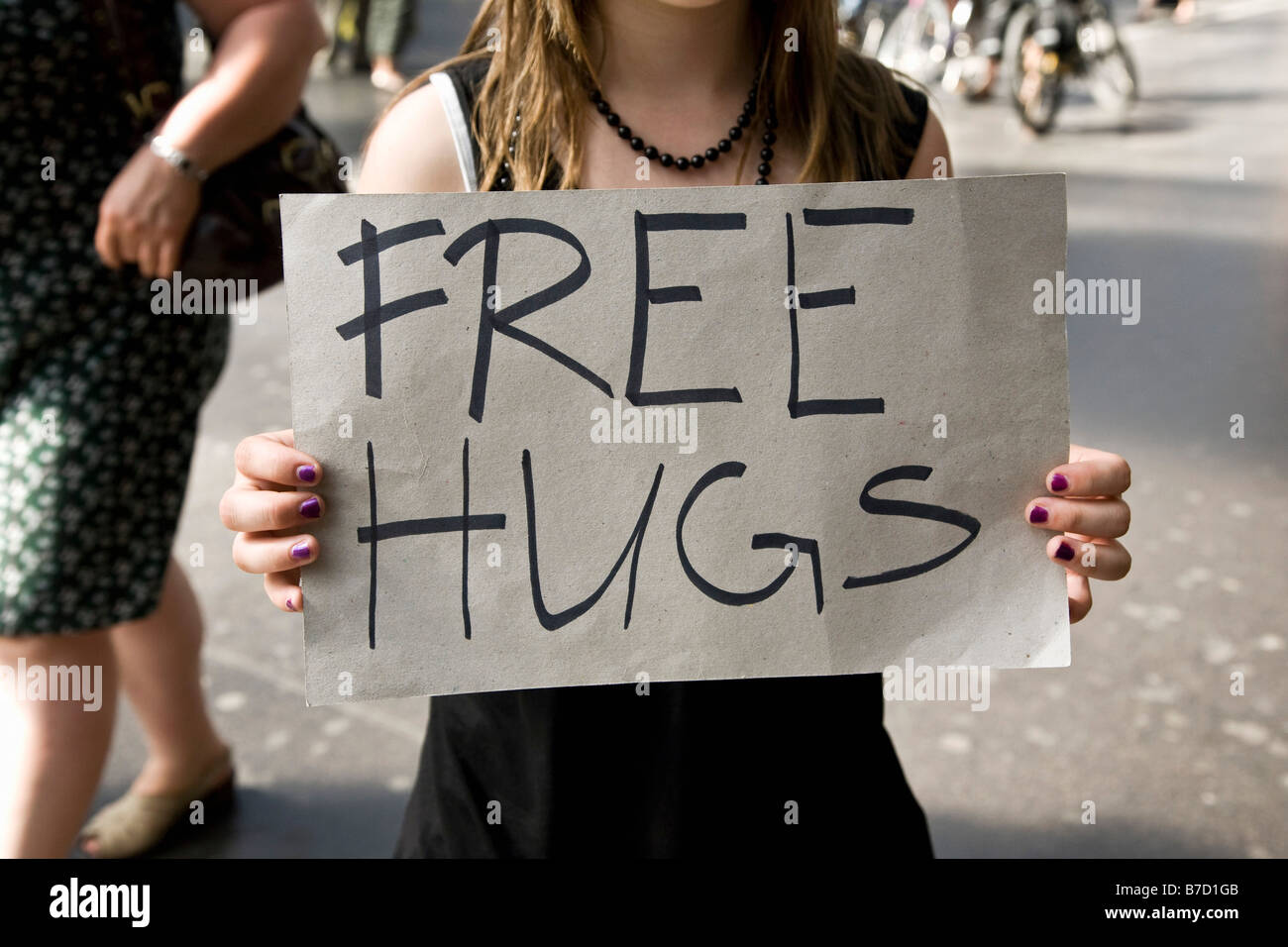 Una giovane donna tenendo un cartello che diceva Free Hugs Foto Stock