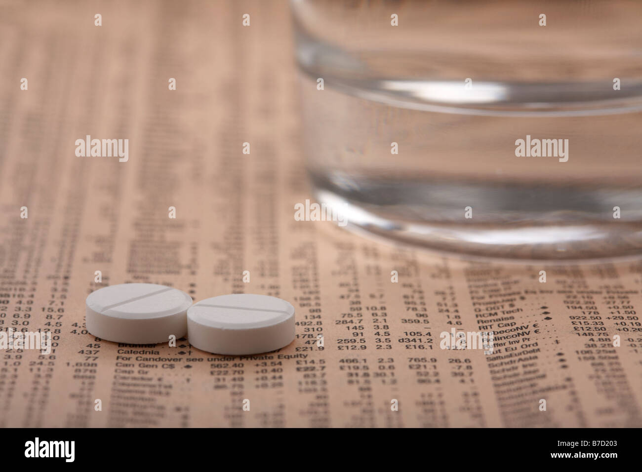 Due paracetamolo aspirina compresse seduto accanto a un bicchiere di acqua su una copia del Financial Times Foto Stock