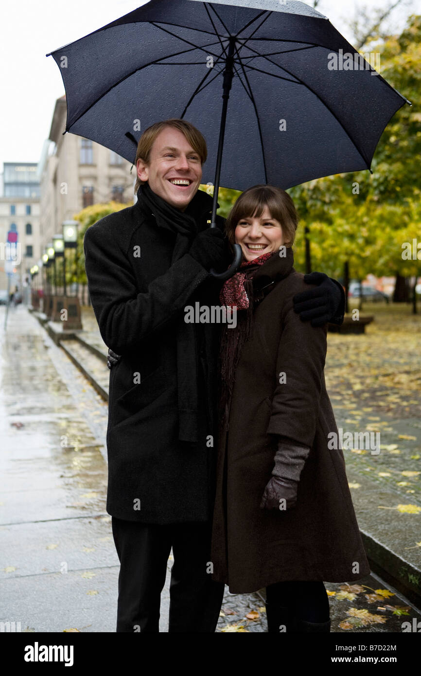 Coppia giovane in piedi e ombrelli azienda Foto Stock