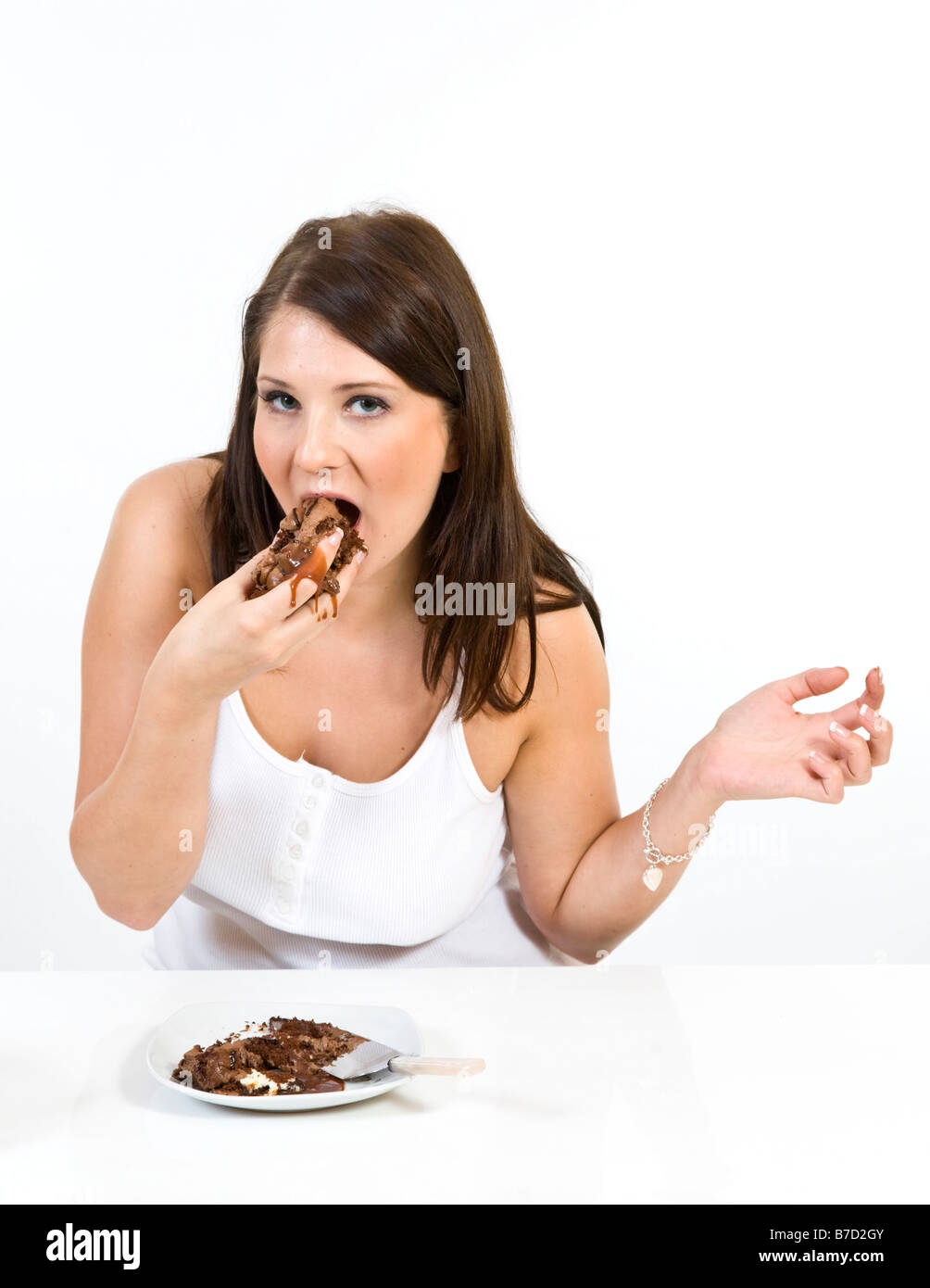 Attraente giovane donna messily mangiare una fetta di torta al cioccolato. Foto Stock
