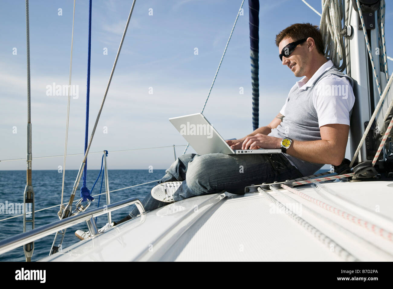 Un uomo che utilizza un computer portatile su un yacht Foto Stock