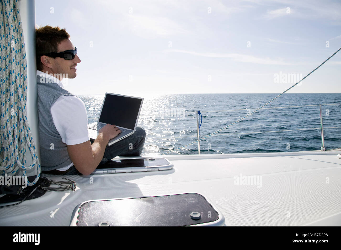 Vista posteriore di un uomo che utilizza un computer portatile su un yacht Foto Stock