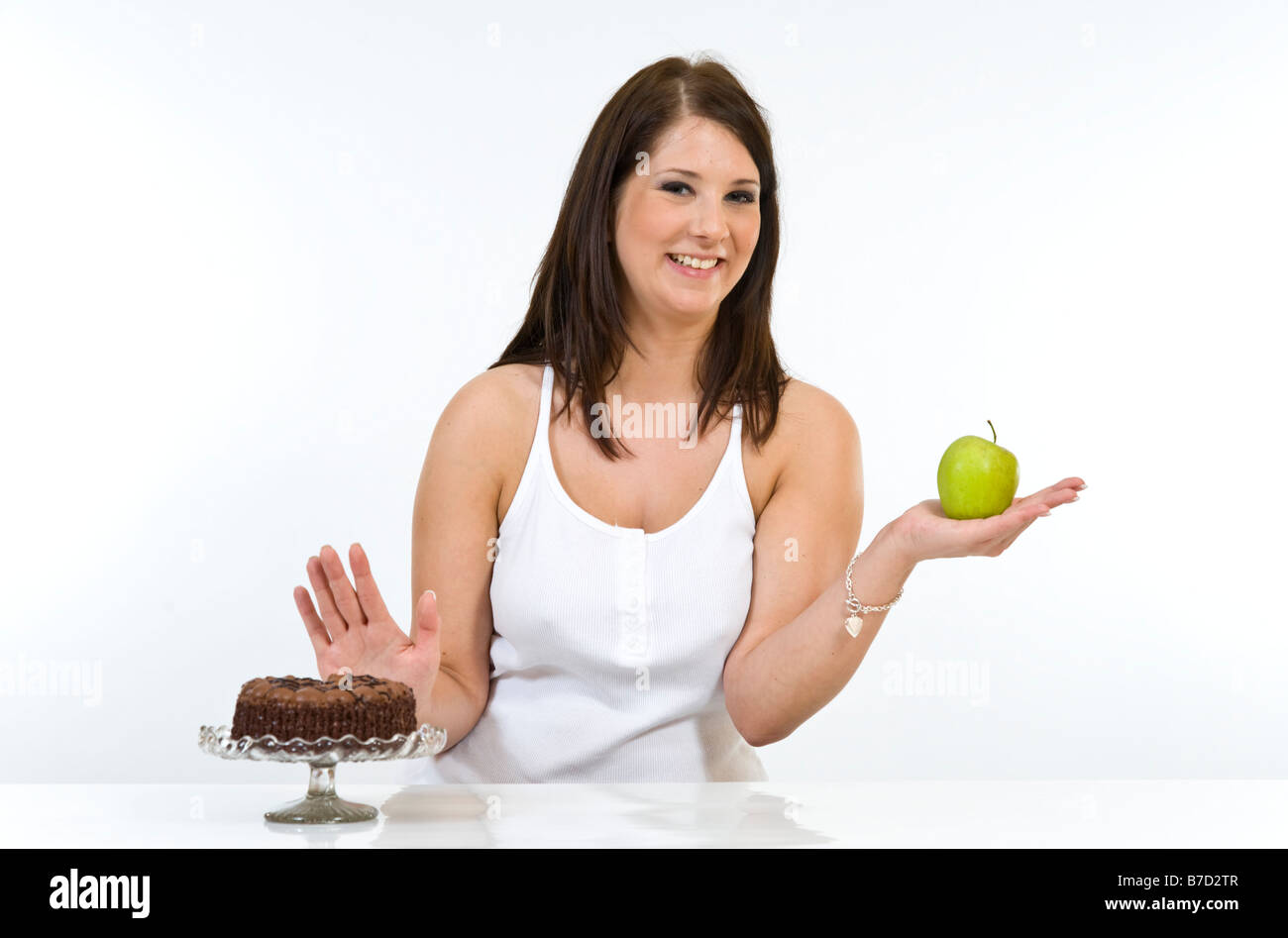 Attraente giovane donna di decidere tra un apple gateau al cioccolato. Foto Stock