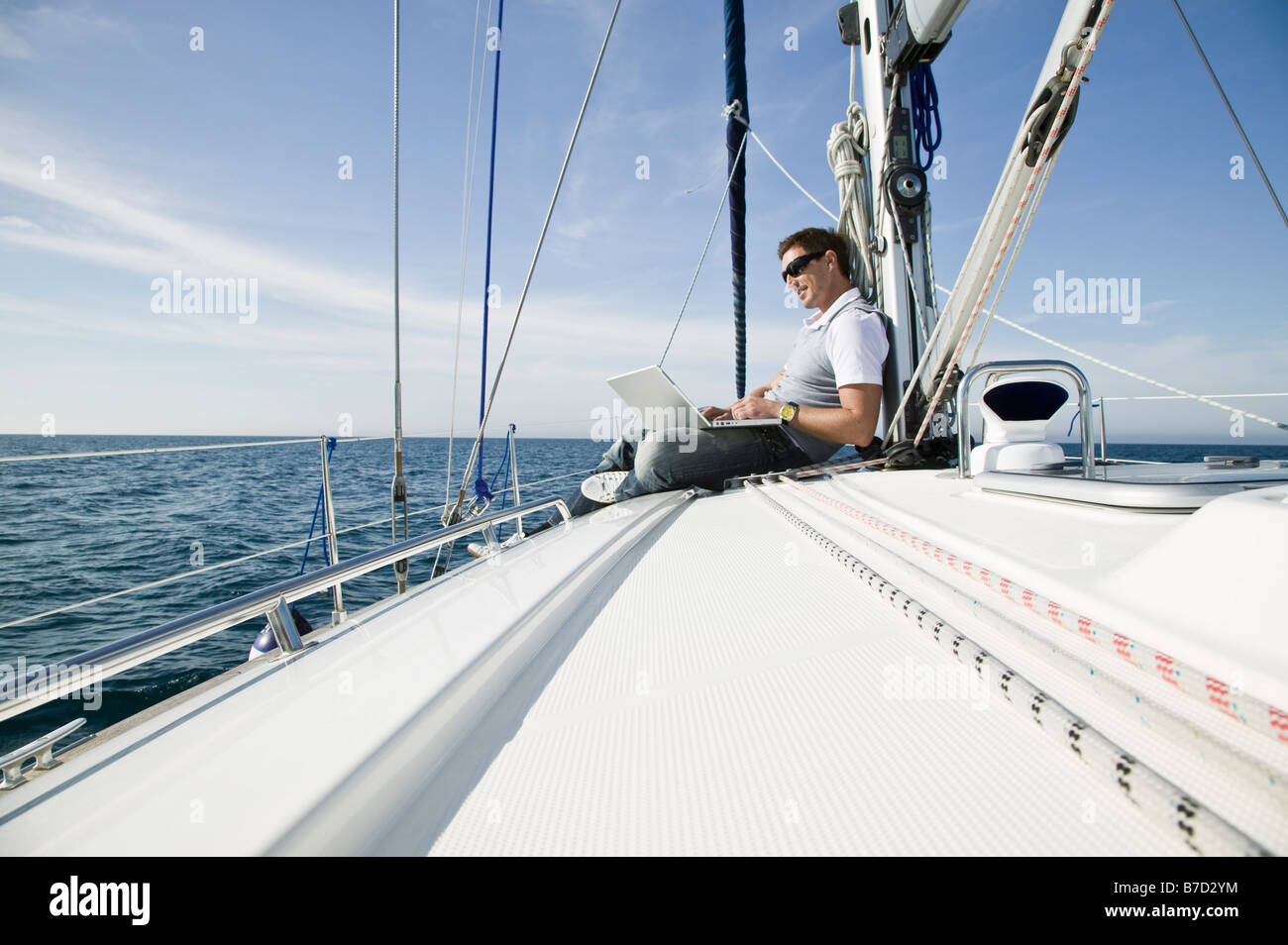 Un uomo che utilizza un computer portatile su un yacht Foto Stock