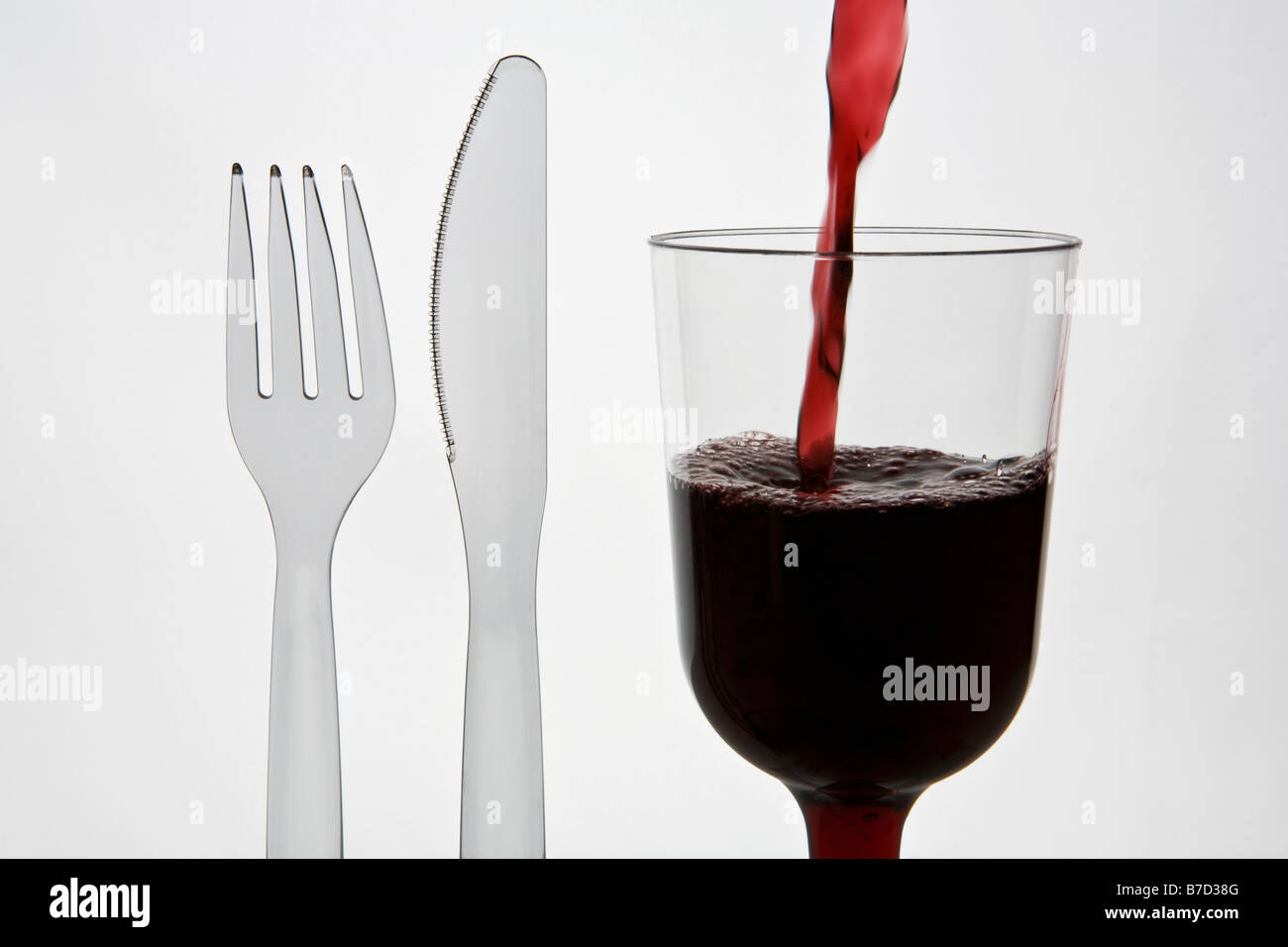 Una plastica coltello e forchetta e un bicchiere di vino rosso Foto Stock