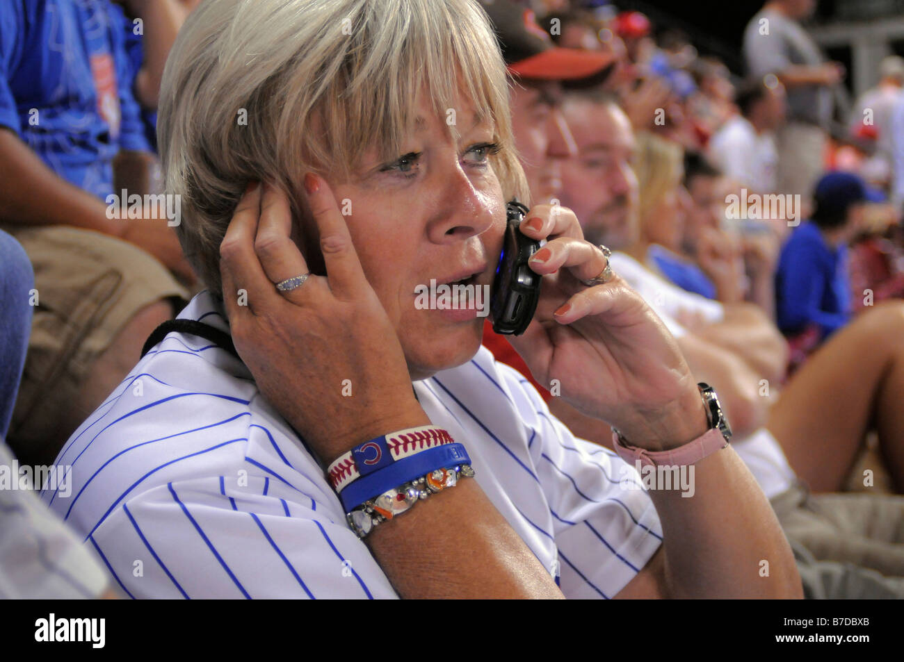 Un centro di età donna americana a parlare su un telefono cellulare a una partita di baseball tra i Cincinnati Reds e il Chicago Cubs. Foto Stock