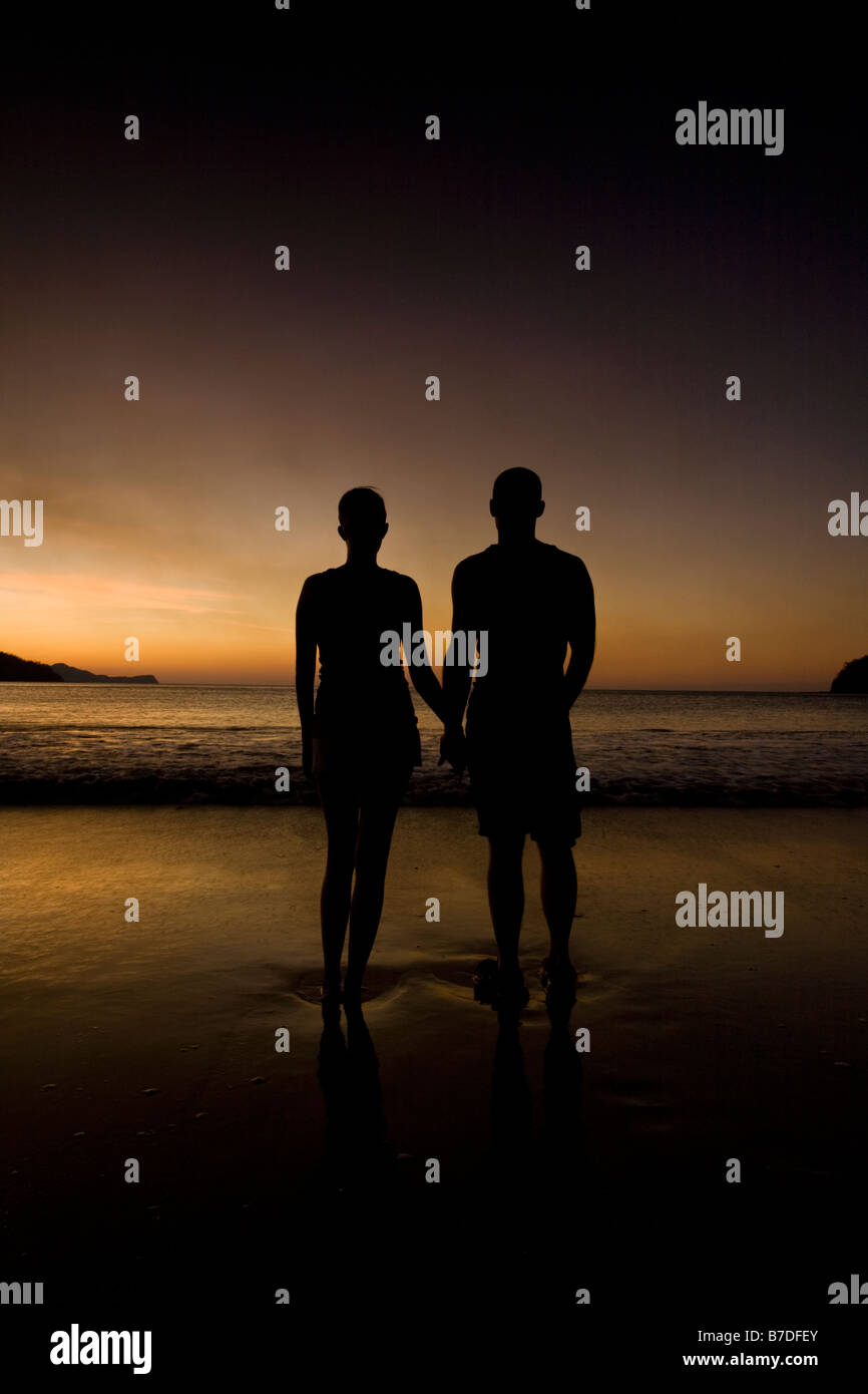 Giovane tenendo le mani mentre si ammira il tramonto sulla spiaggia in Costa Rica. Foto Stock