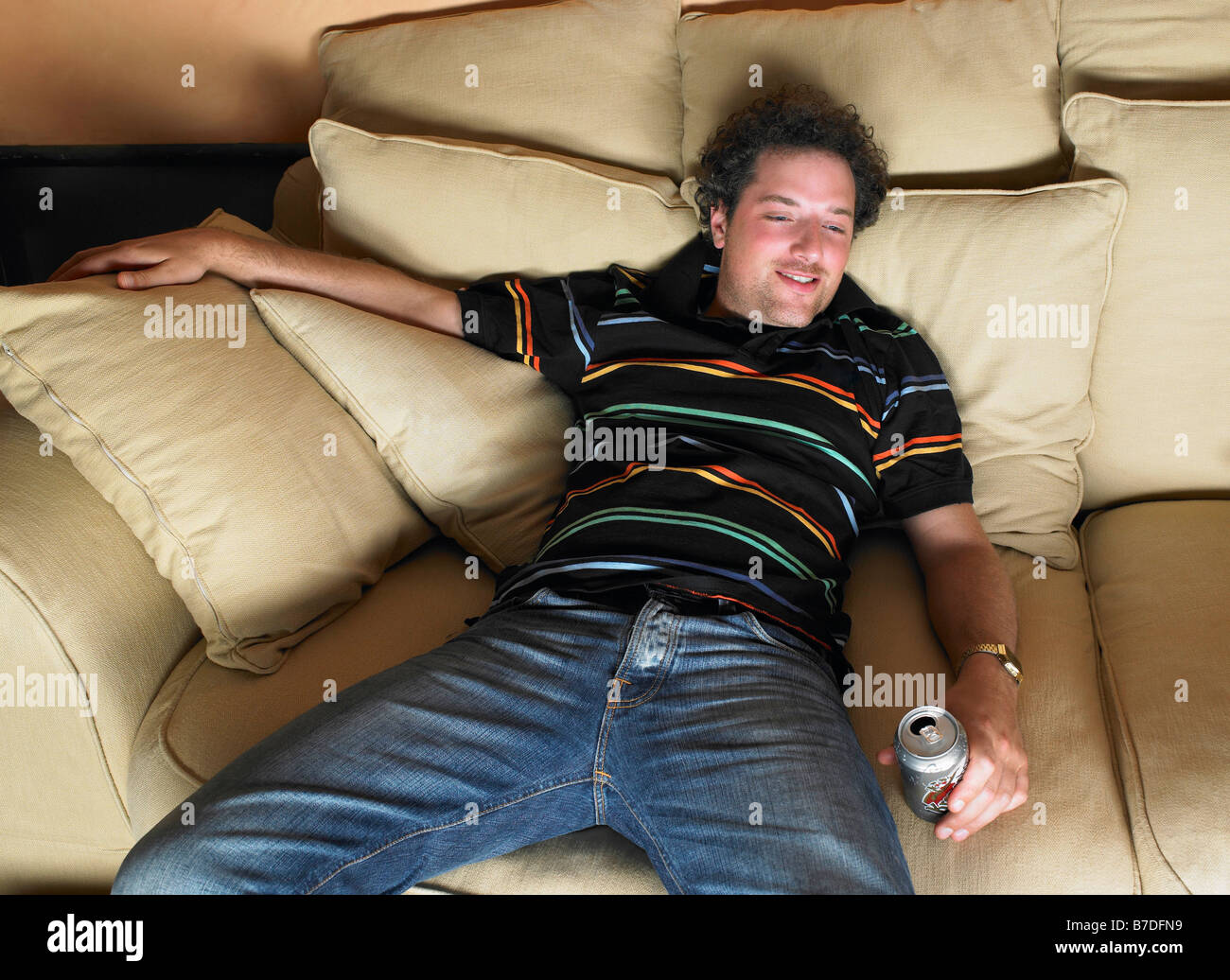 Uomo di guardare la televisione, tenendo una birra Foto Stock