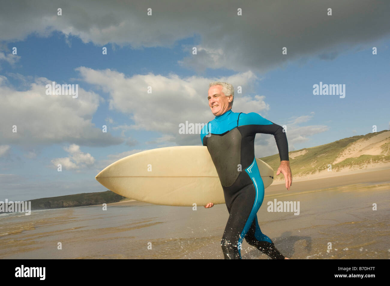 Esecuzione maschio in mare con una tavola da surf Foto Stock