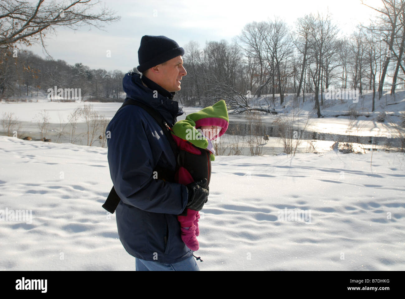 Un uomo cammina con la sua figlia infante attraverso la neve in un parco della città di New Haven CT STATI UNITI D'AMERICA Foto Stock