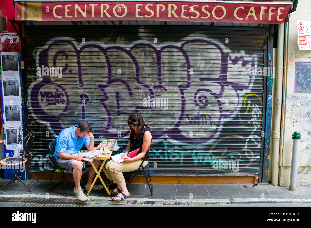 Un paio di stop per leggere i loro giornali al di fuori di un bar caffè in uno di Melbourne s laneways stretta Foto Stock
