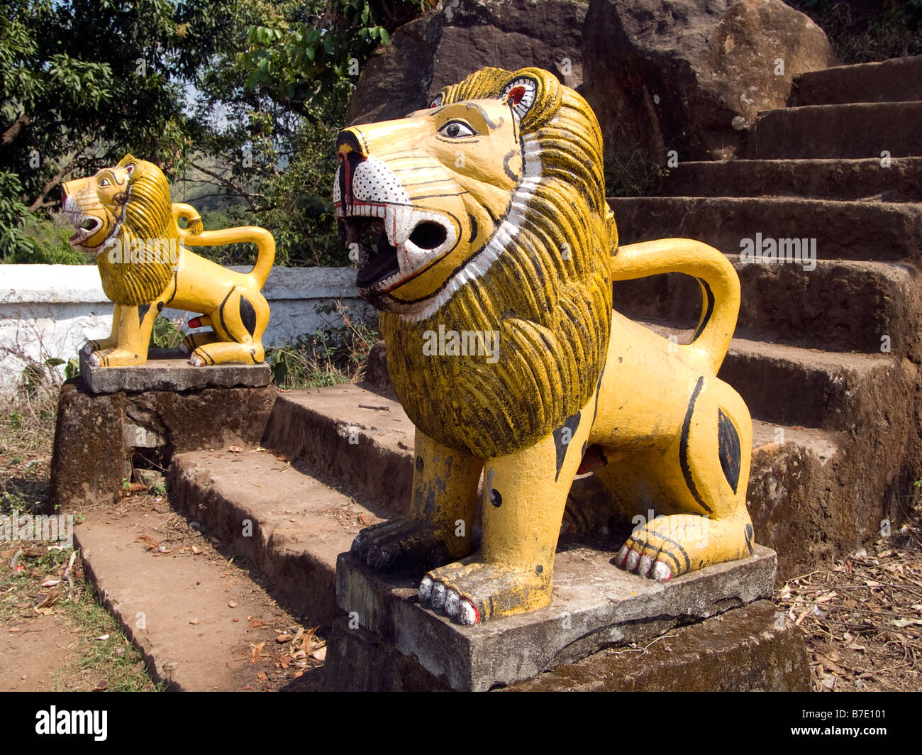 Ingenuo dipinto in giallo lions custode fiancheggiano il passi per un tempio indiano Foto Stock