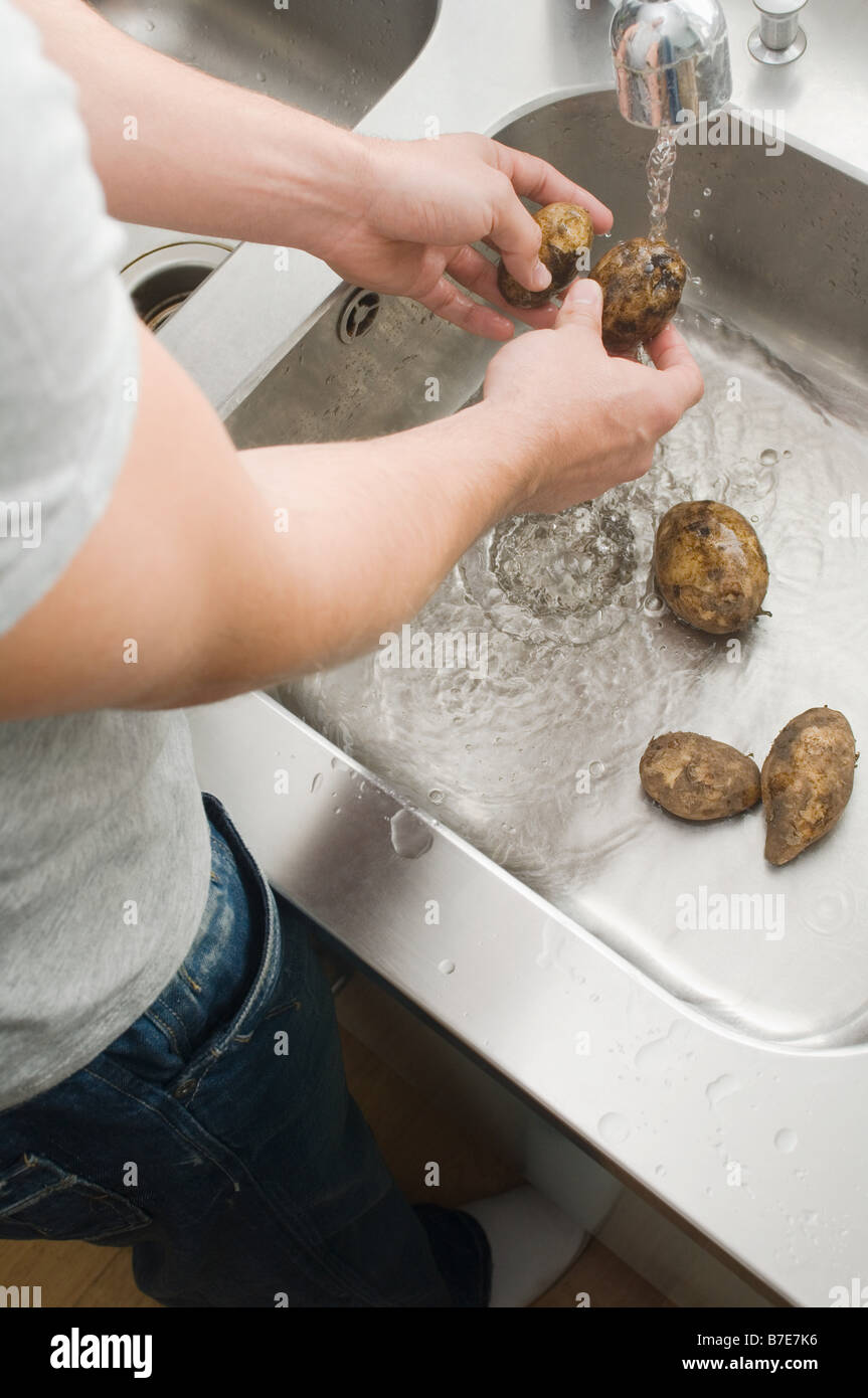 L'uomo lavare le patate Foto Stock