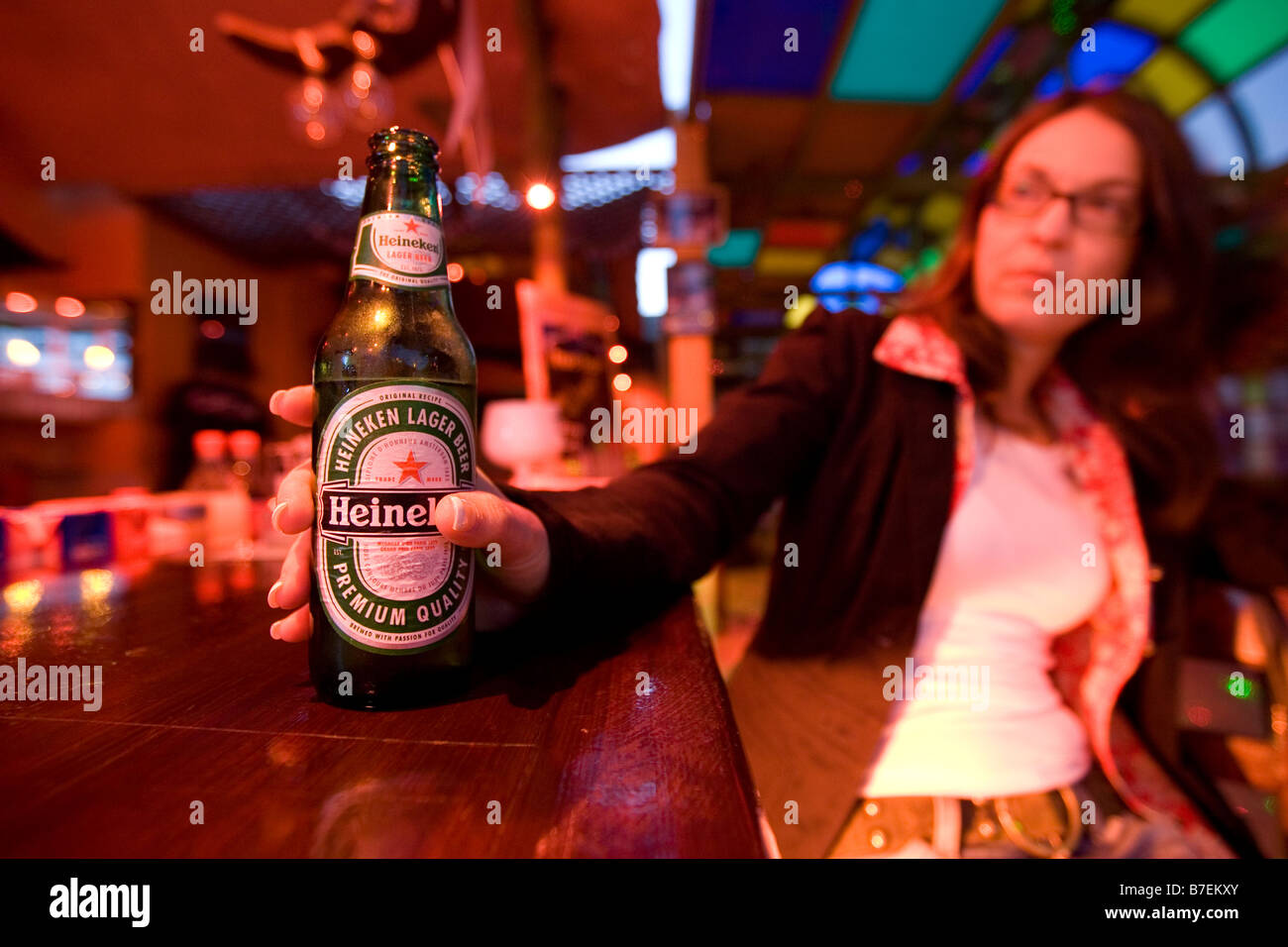 Una donna afferra una bottiglia di Heineken in un bar a Dahab, Egitto Foto Stock
