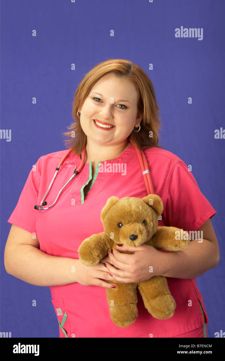 Giovane donna in nurse scrubs uniforme con uno stetoscopio e orsacchiotto Foto Stock