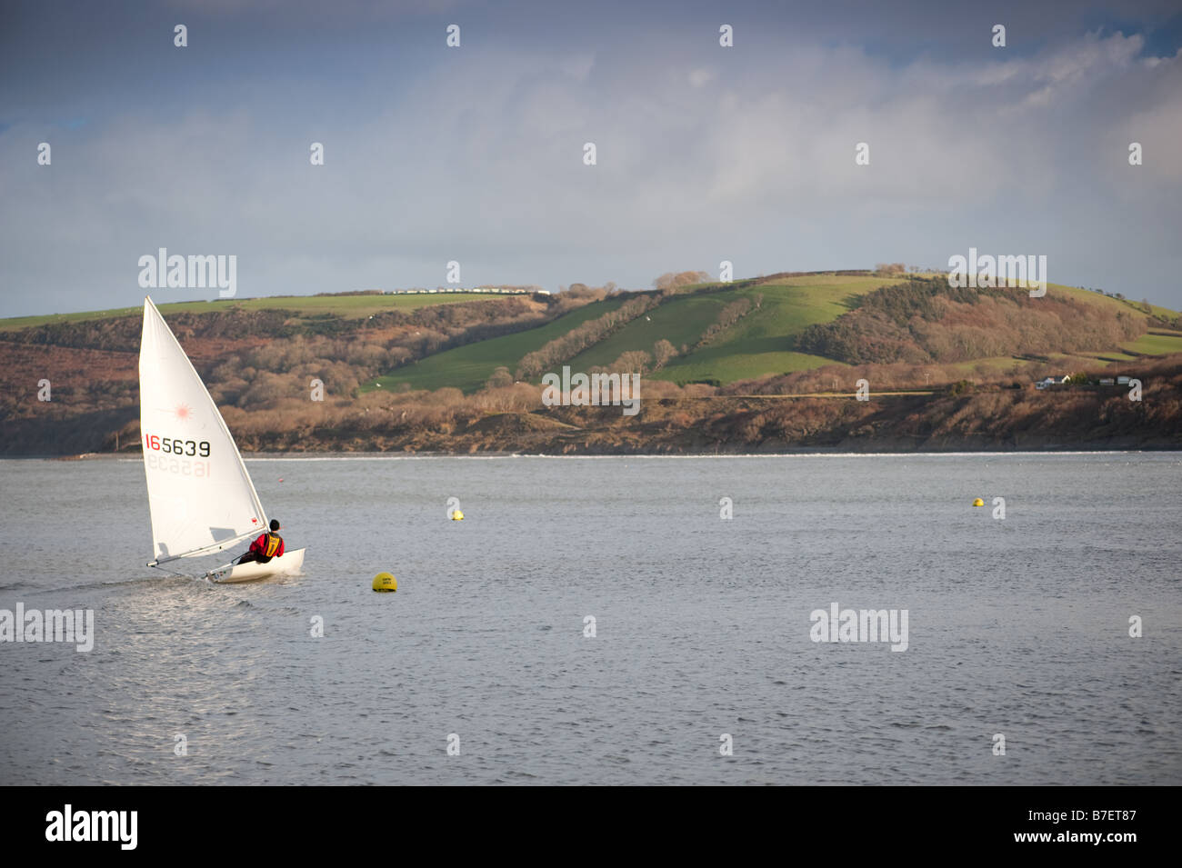 Pomeriggio invernale un uomo vela il suo piccolo dinghy in mare al largo di New Quay Galles Ceredigion REGNO UNITO Foto Stock