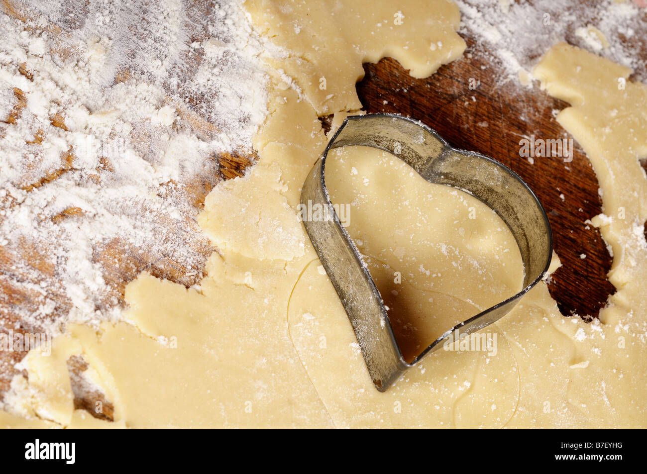 Foto di stock di un cuore a forma di biscotto frollino essendo tagliato dall'impasto Foto Stock